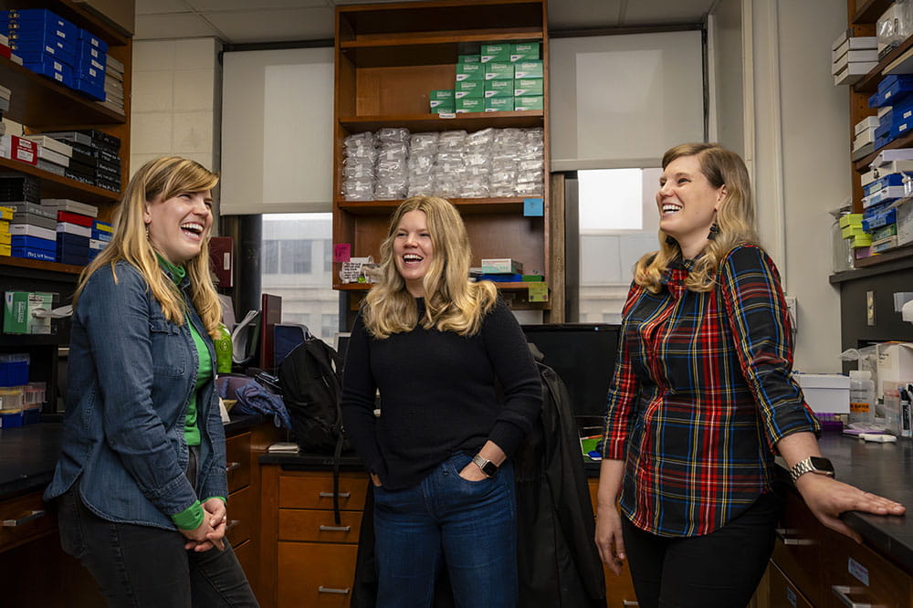 three women laugh in a moment of levity in a research lab